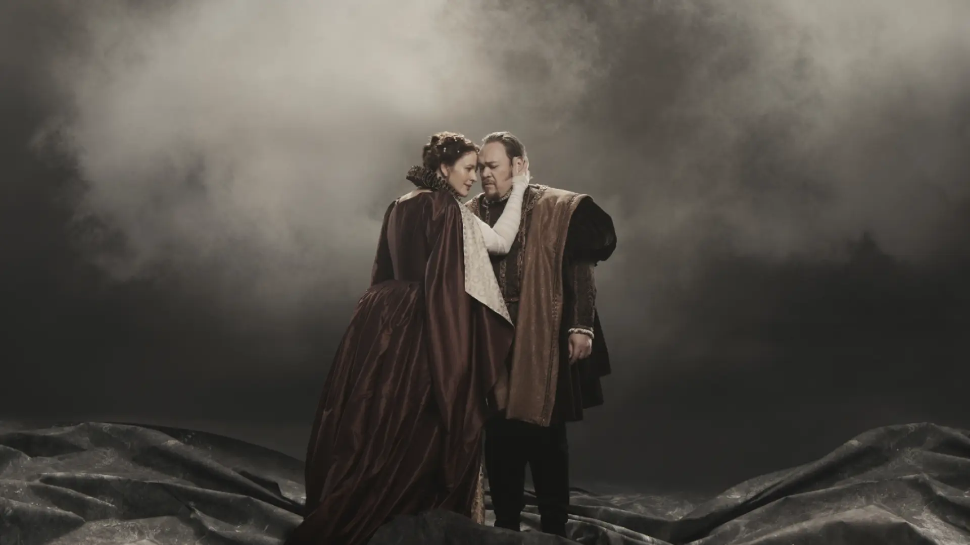Woman playing Lady Macbeth presses her forehead to forehead of man playing Macbeth on smoky stage at the Met